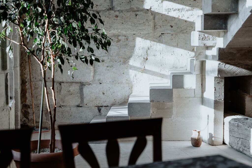 Sunlit interior featuring stone walls, houseplant, and unique stone steps.