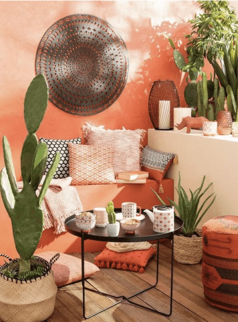 Ambiance mexicaine pour ce patio aux couleurs vives et chaleureuses, rose, rouge, orange, petite table en aluminium noir, nombreux coussins et Bougies pour des soirées festives, cactus et plantes du désert