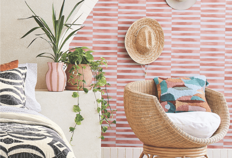 Ambiance du sud pour cette chambre lumineuse, un fauteuil en rotin accompagné de plantes et d'un chapeau